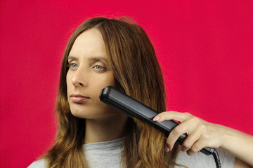 Caucasian woman, girl flattens her hair with a Curling iron