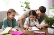 © New Africa - Father helping his daughters with homework at table indoors