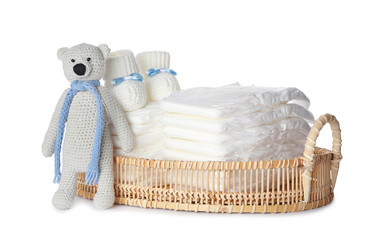 Wall Mural - wicker tray with disposable diapers, toy bear and child's booties on white background