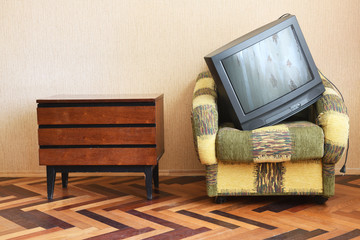 Wall Mural - The old TV lies in a vintage armchair.Old design in a home.