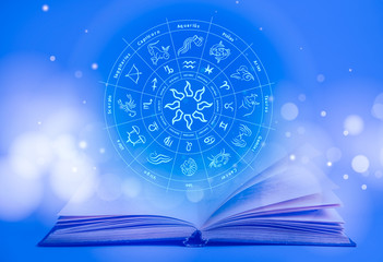 Wall Mural - Open book and illustration of zodiac wheel with astrological signs on blue background