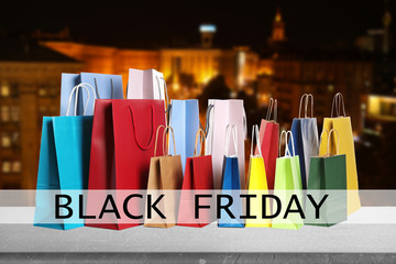 Black Friday. Many shopping bags and blurred cityscape on background