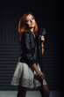 © omelnickiy - young red-haired girl in a white dress and a black leather rocker jacket sings into the microphone