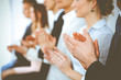 © rogerphoto - Business people clapping and applause at meeting or conference, close-up of hands. Group of unknown businessmen and women in modern white office. Success teamwork or corporate coaching concept