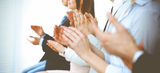 Business people clapping and applause at meeting or conference, close-up of hands. Group of unknown businessmen and women in modern white office. Success teamwork or corporate coaching concept