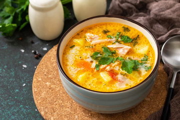 Norwegian Soup with cream and salmon on a rustic wooden table on a dark stone background. Copy space.