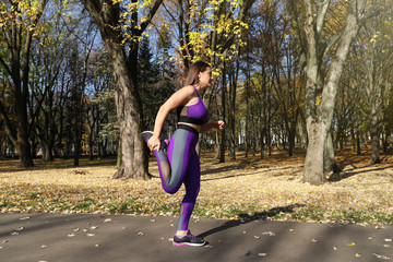 A girl in a tracksuit is warming up in the park before running. Exercise in the fresh air