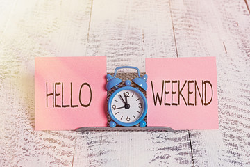 Writing note showing Hello Weekend. Business concept for Getaway Adventure Friday Positivity Relaxation Invitation Mini blue alarm clock standing above buffer wire between two paper