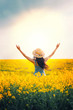 © kharchenkoirina - Back Silhouette Woman raised her hands to sky, sun, sunset. Blue dress straw trendy hat. Field rape yellow flowers. Long hair brunette fly in motion wind. Concept religion prayer blessing divine light