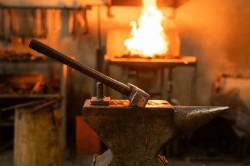 Hammer and anvil in forge on blurred background