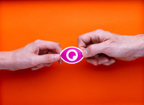 Surveillance internet, illustration avec un pictogramme oeil imprimé, tenu par deux mains en opposition, sur fond orange.