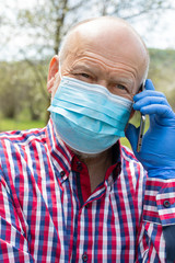 Canvas Print - Elderly man with mask and gloves talking on the phone