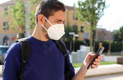 COVID-19 Mobile Application Young Man Wearing KN95 FFP2 Mask Using Smart Phone App in City Street to Aid Contact Tracing and Self Diagnostic in Response to the Coronavirus Pandemic 2019