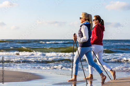 Cuadros en Lienzo Nordic walking - two women working out on beach