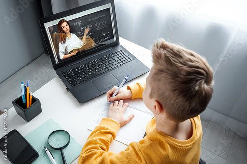 Cuadros en Lienzo Distance learning, a boy learns math while looking at a laptop beech during an online lesson