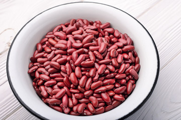 Metal bowl of red raw beans on a light wooden background