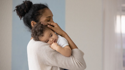 Wall Mural - caring young biracial mother hold lean to chest cute little infant toddler, loving african american 