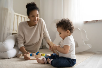 Wall Mural - happy young biracial mother sit on floor play with building blocks bricks with little infant toddler