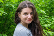 © Tania - beautiful young girl on a background of green leaves of trees. Close-up.