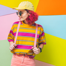 Fashionable Model With Pink Hair And Backpack In Yellow Cap And Sunglasses On Colorful Background. Back To School Concept. Minimal