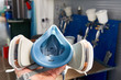 Professional respirator in auto repair shop with spray guns on background