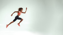 Never Give Up. Full Length Of Young African Woman With Perfect Body In Sports Clothing Jumping In Studio Against Grey Background