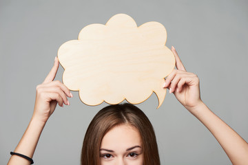 Cropped woman face holding thinking bubble above