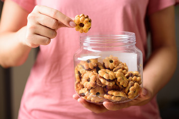 Cracker with pineapple jam (flower shape) in bottle jar holding and eating by woman hand, Thai snack