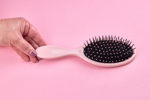 Woman Take A Pink Hairbrush Isolated On A Pink Coral Background With Space. Beauty Hair Accessory For Hairstyle.