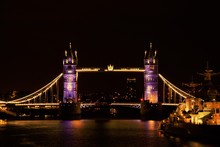 Illuminated Suspension Bridge Over River At Night