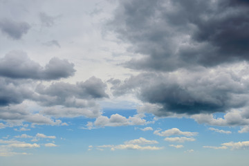 Wall Mural - Dark thunderclouds are approaching the blue sky with white clouds. Change of weather from sunny to rainy. Dramatic skyscape.