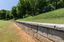 Long Low Retaining Wall Along A Hillside In A Public Park, Green Grass And Trees, Horizontal Aspect