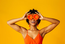 Portrait Of A An Excited Young Woman With Orange Gerbera Daisies Covering Her Eyes
