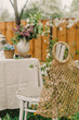 Details of tables decorated in the spring garden for a photoshoot or wedding reception with lilac. Bag with flowers on the chair