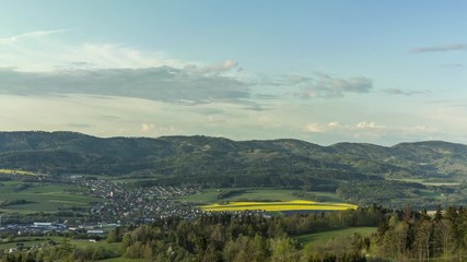 Wall Mural - Village timelapse of moving clouds that lies in a mountainous area surrounded by hills White clouds move rapidly in sky shadows change  land full of nature and fields around village of Zasova