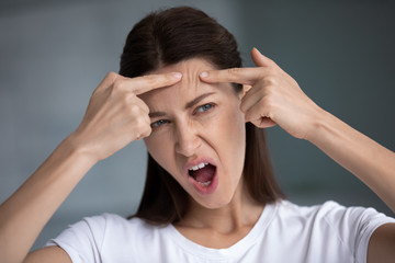 Close up of woman looks in mirror feel stressed about facial skin problems push skin squeezes pimple on forehead, need chemical peeling, aesthetic medicine, cosmetology, skincare and treatment concept