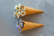 Bouquet Of Chamomiles In A Waffle Cone On A Gray Background. The Flowers Are Blooming. Wildflowers.
