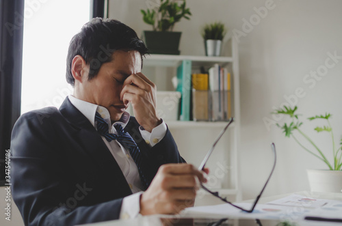 Fotografía tired asian young businessman feeling stressed and taking off eyeglasses feels e