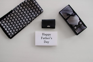 Wall Mural - Happy Fathers Day inscription with tie, tool kit or wallet, mens scarf, box with a tie and cufflinks with a bow on white background. Greetings and presents. white card, congratulationfor man, flatlay