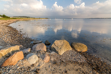 Scenic beach with rocks and boats in the background at the Baltic Sea during sunrise