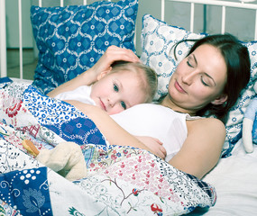 Wall Mural - mother with daughter together in bed smiling, happy family closeup, lifestyle people concept, cool real modern family