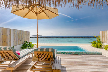 Canvas Print - Beautiful poolside and blue sky beach. Luxurious tropical beach landscape from private villa with deck chairs loungers and sea water. Summer travel vacation landscape. Exotic tourism landscape view