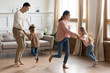 © fizkes - Happy parents dancing with little daughter in living room, excited mother and father holding cute preschool girls hands, moving to favorite music, spending weekend together, funny family activity
