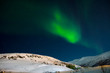 Zorza polarna nad zaśnieżonym wzgórzem. Zorza w Norwegii
