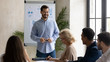 © fizkes - Laughing handsome businessman flip charts presentation new project in boardroom at company meeting. Confident coach auditor speaks and waiting decision with diverse colleagues using board and graphs.