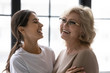 © fizkes - Close up laughing mature mother and adult daughter enjoying tender moment. Happy relaxing young woman and older mum hugging looking at each other and having fun together, two generations bonding.