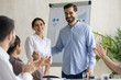 © fizkes - Smiling young businesswoman takes congratulations clap hands from diverse colleagues after flip charts presentation in boardroom at company meeting. Happy auditor standing in front of board.