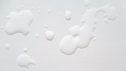 Spilled water on a white textured surface. Background. Top view.