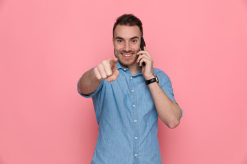 Poster - casual man pointing forward, smiling and talking on the phone