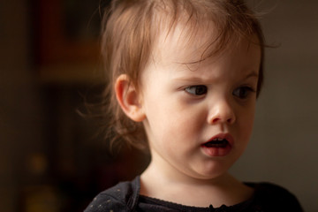 Close-up portrait of a little cute white baby with a dirty face in soft light and blurry background